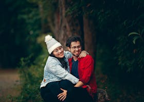 Happy couple sitting together in a green park, enjoying a joyful moment filled with love and affection.