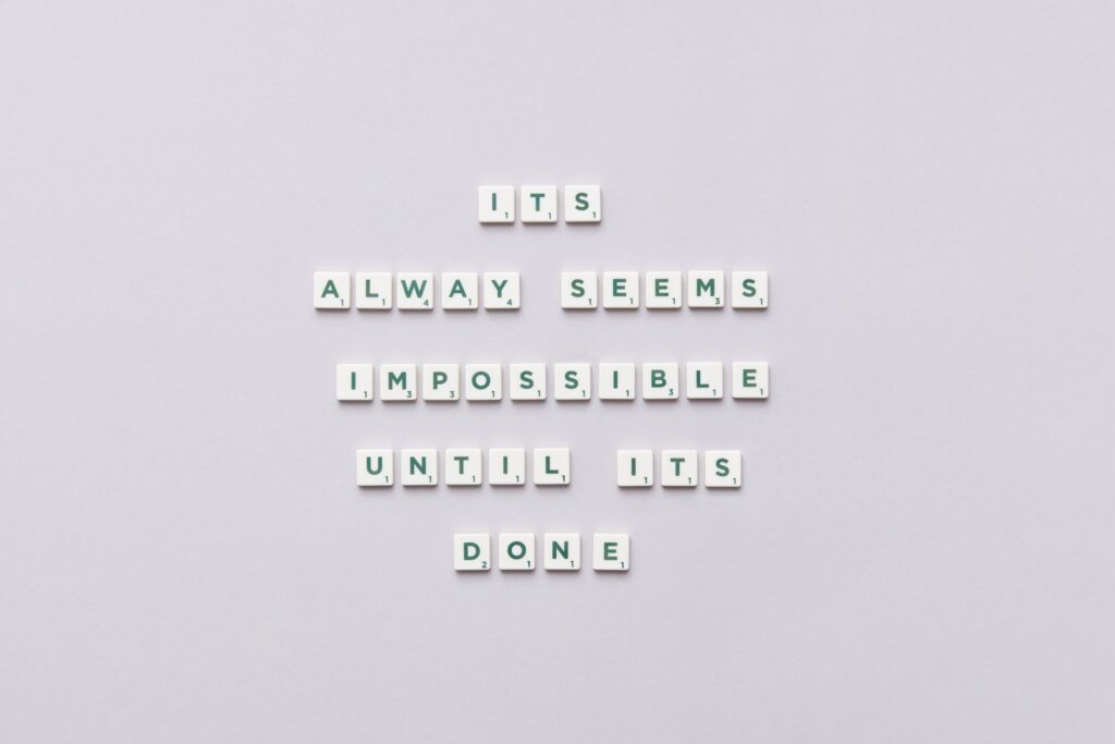 Motivational quote 'It always seems impossible until it's done' in Scrabble tiles.